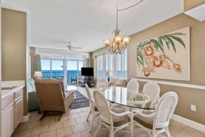 a dining room with a glass table and white chairs at Jade East Towers 1850 in Destin