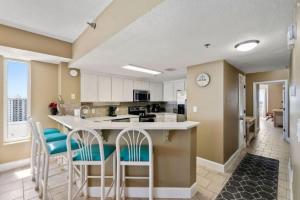 a kitchen with white cabinets and a counter with chairs at Jade East Towers 1850 in Destin