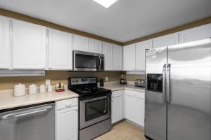 a kitchen with white cabinets and a stainless steel refrigerator at Jade East Towers 0740 in Destin +44 photos