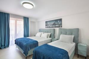 two beds in a hotel room with blue curtains at Hotel Tommy in Budva +49 photos