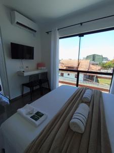 a bedroom with a large bed with a large window at Suíte 25 família Praia de Leste in Pontal do Paraná