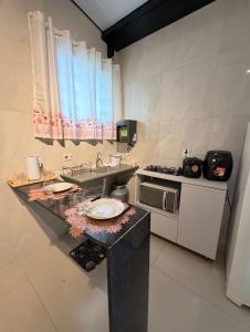 a kitchen with a counter with a sink and a stove at Flat 02 - Ar condicionado ao lado do Camaru, próximo ao UMC e shopping in Uberlândia