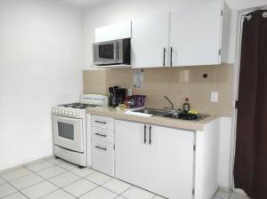 a kitchen with white cabinets and a white stove top oven at Departamento Privado in Guadalajara