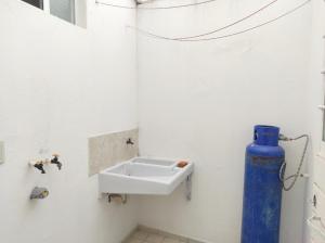 a white bathroom with a sink and a blue bottle at Departamento Privado in Guadalajara