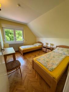 a room with two beds and a chair and a window at Tiszafa Apartman in Csopak