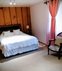 a bedroom with a bed and a chair and a window at Hostal los arrayanes in Puerto Carmen