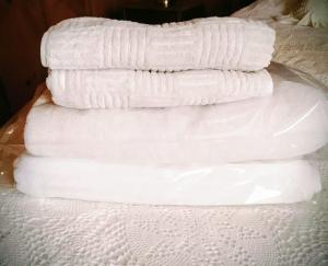 a stack of white towels stacked on top of a bed at Hostal los arrayanes in Puerto Carmen