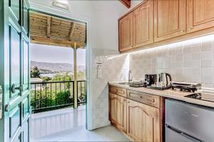 Una cocina con muebles de madera y un balcón. en Villa Eftichia Hotel Apartments & Studios, en Kontokali