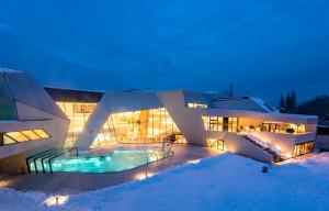 ein großes Gebäude mit Schwimmbad im Schnee in der Unterkunft Hotel Marko in Nötsch