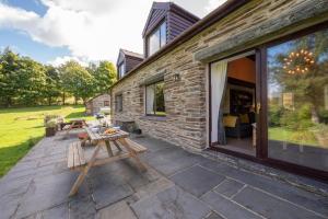 a patio with a wooden picnic table next to a building at 4 Bed in Ffestiniog oc-bow172 in Ffestiniog