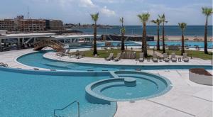 a large swimming pool with palm trees and the ocean at Sonoran Star Signature 3-Bedroom Beachfront Luxury Condominium in Puerto Peñasco