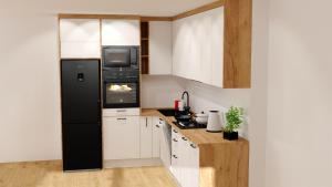 a kitchen with a black refrigerator and white cabinets at Cosy Space Apartment in Tychy