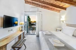Un dormitorio con una cama y un televisor y un balcón. en Villa Eftichia Hotel Apartments & Studios, en Kontokali
