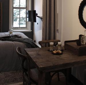 a room with a table and a bed and a table and a table at Het Verborgen Jagershuisje in Wedde