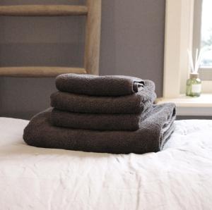 a stack of towels sitting on top of a bed at Het Verborgen Jagershuisje in Wedde