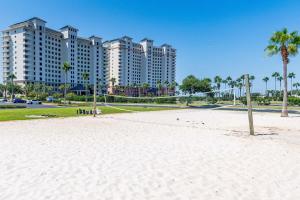 a beach in front of a large building with palm trees at Beach Club 806A by Youngs Suncoast in Gulf Highlands