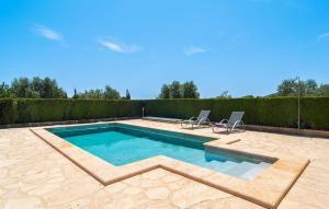 a swimming pool with two chairs in a backyard at Es Cipres in Porreres