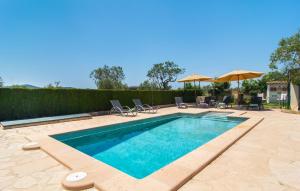 a swimming pool with chairs and umbrellas on a patio at Es Cipres in Porreres