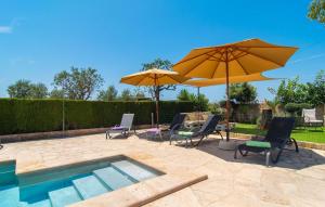 a patio with two umbrellas and chairs and a pool at Es Cipres in Porreres