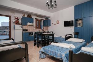 a room with two beds and a kitchen with blue cabinets at Irini Studios in Psarou