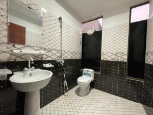 a bathroom with a sink and a toilet and a mirror at Own It Hotel in Islamabad