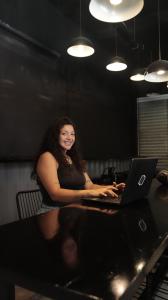 a woman sitting at a table with a laptop computer at Graffi City House in Florianópolis