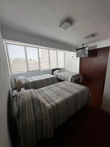 a hotel room with two beds and a window at Éclat Hotel Boutique in Iquique
