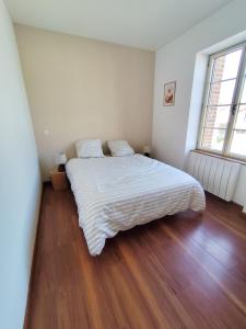 a bedroom with a large white bed with a wooden floor at La petite Amandaise in Saint-Amand-sur-Sèvre