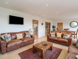 a living room with brown leather couches and a table at Lurach House in Appin