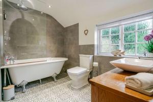 a bathroom with a tub and a toilet and a sink at The Knutsford Cottage in Knutsford