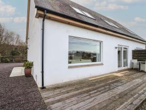 a white house with a large window on a deck at Lurach House in Appin