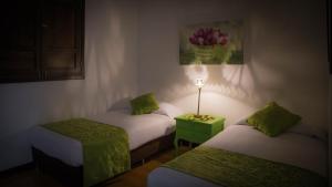Zimmer mit 2 Betten und einem Tisch mit einer Lampe in der Unterkunft La Posada de la Plaza in Salento