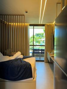 a bedroom with two beds and a desk and a balcony at Flat Lindo em Muro Alto Resort Beach Class Verano Porto de Galinhas in Porto De Galinhas +33 photos