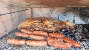 a chicken and sausages cooking on a grill at Umbral del valle in Valle Hermoso
