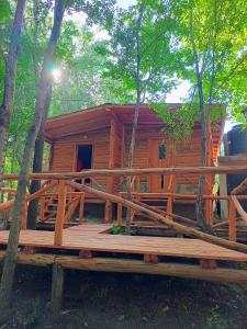 a wooden cabin in the woods with a large deck at Umbral del valle in Valle Hermoso
