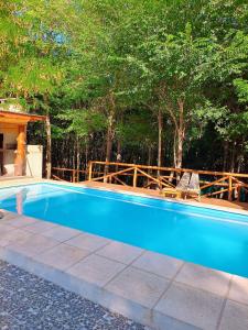 a blue swimming pool with two chairs and trees at Umbral del valle in Valle Hermoso