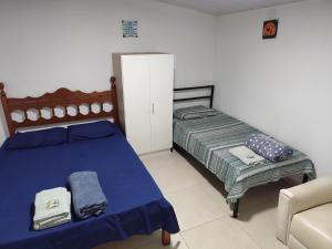 a bedroom with a blue bed and a chair at Pousada 4 Estações in Botucatu