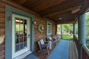 a porch of a log cabin with chairs and a door at Tree Haus by Railey Vacations in Oakland