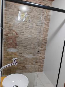 a bathroom with a glass shower with a sink at Pousada Anabela in Campo Alegre +5 photos