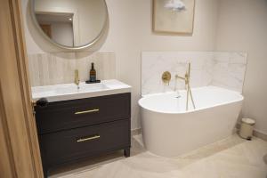 a bathroom with a tub and a sink and a mirror at Highland House in Lochearnhead +37 photos