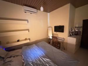 a bedroom with a bed and a desk and a television at Nara Cíntia in Luanda