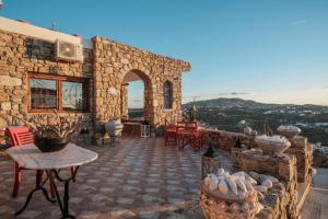 a stone house with a patio with tables and chairs at Irini Studios in Psarou