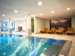 a swimming pool in a house with chairs at Gästehaus Weller in Oberstdorf
