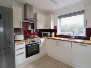 a kitchen with white cabinets and a sink and a window at Sealladh in Appin