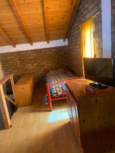 a bedroom with a bed and a desk with a television at Torres del Piltri in El Bolsón