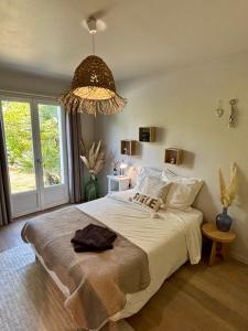 a bedroom with a large bed and a chandelier at Villa avec piscine Proche de ROYAN in Sémussac
