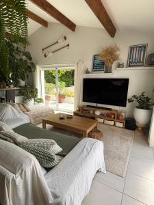 a living room with two couches and a flat screen tv at Villa avec piscine Proche de ROYAN in Sémussac