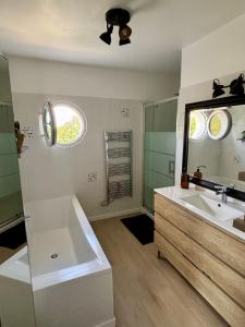 a bathroom with a tub and a sink and a mirror at Villa avec piscine Proche de ROYAN in Sémussac +26 photos