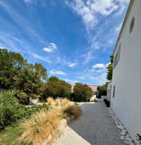 a pathway leading to a building with a blue sky at Villa avec piscine Proche de ROYAN in Sémussac