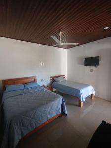 a bedroom with two beds and a flat screen tv at Las Morenas in Nosara +22 photos